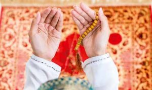 Islamisches Gebet, Blick von oben auf ausgestreckte Hände, Gebetskette und Gebetsteppich